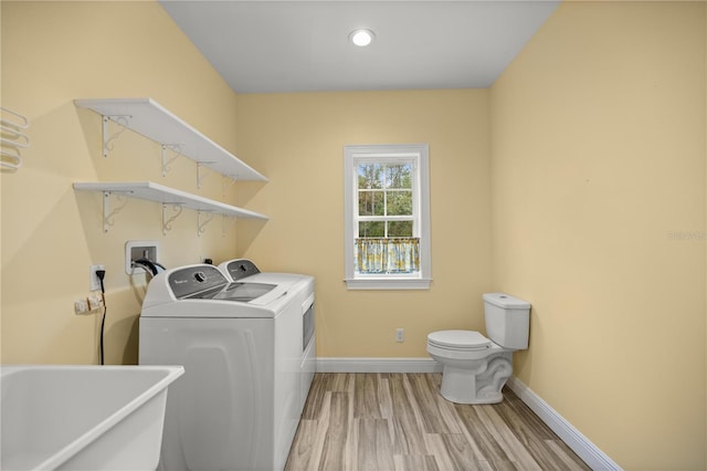 laundry room with sink, washer and clothes dryer, and light hardwood / wood-style flooring