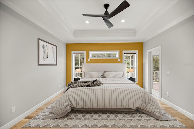 bedroom with ceiling fan, a tray ceiling, access to exterior, and light hardwood / wood-style flooring