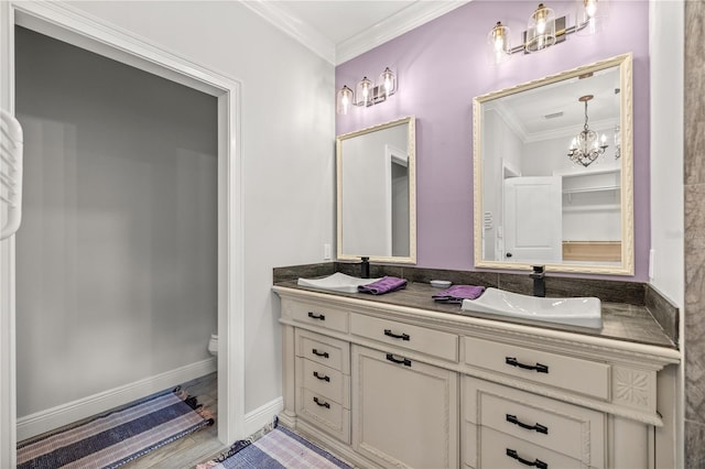 bathroom featuring a notable chandelier, ornamental molding, vanity, and toilet