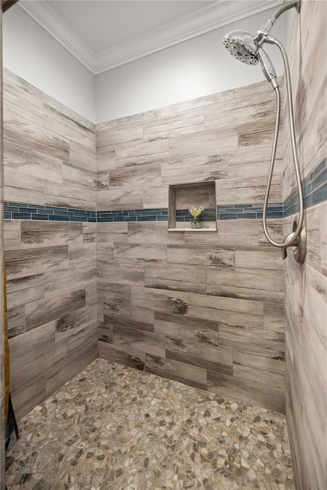 bathroom with crown molding and a tile shower