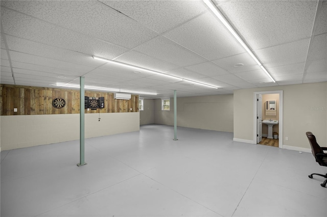 basement featuring a drop ceiling, sink, and an AC wall unit