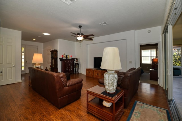 living room with dark wood-type flooring, a textured ceiling, and ceiling fan