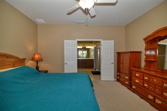 bedroom featuring ceiling fan, light colored carpet, and ensuite bath