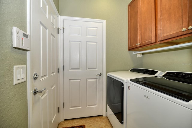 clothes washing area featuring washer and clothes dryer, cabinets, and light tile patterned flooring