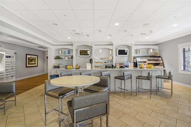 kitchen featuring built in shelves, a kitchen breakfast bar, and light tile patterned flooring