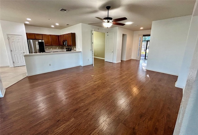 unfurnished living room featuring a ceiling fan, baseboards, visible vents, and wood finished floors