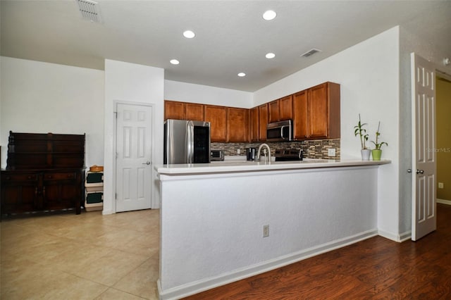 kitchen with stainless steel appliances, visible vents, a peninsula, and tasteful backsplash