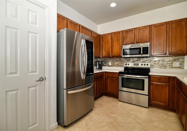 kitchen featuring appliances with stainless steel finishes, light countertops, backsplash, and light tile patterned flooring