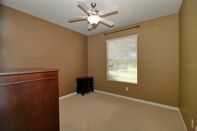 interior space featuring light carpet, a ceiling fan, and baseboards