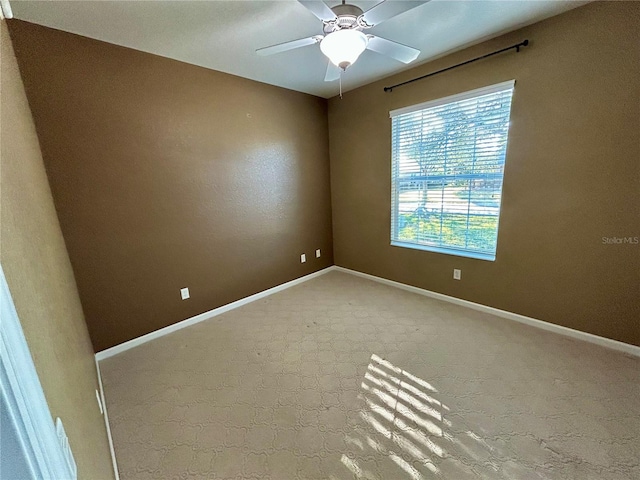 carpeted spare room featuring ceiling fan and baseboards