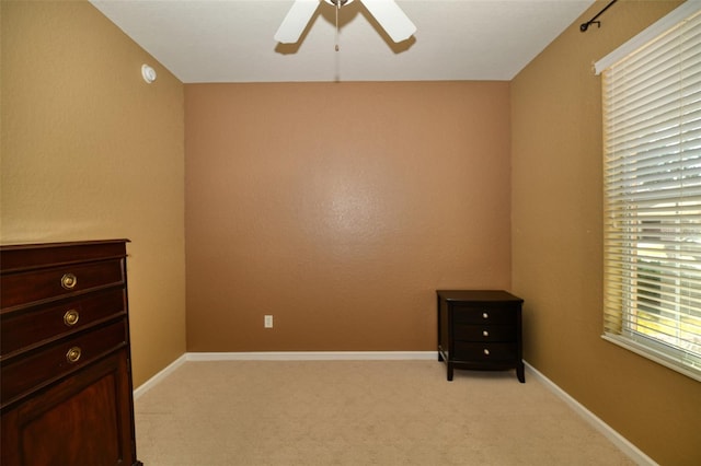 empty room featuring light carpet, baseboards, and a ceiling fan