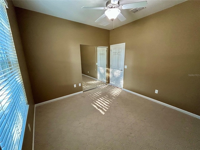 spare room featuring ceiling fan, carpet, visible vents, and baseboards