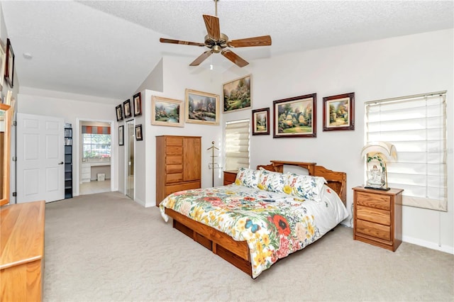 carpeted bedroom with ensuite bathroom, lofted ceiling, a textured ceiling, and ceiling fan