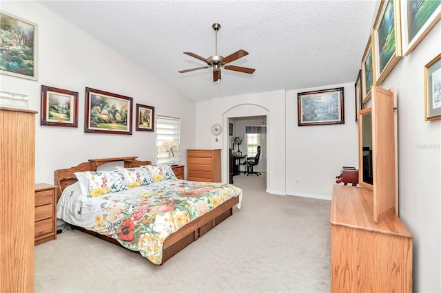 carpeted bedroom with a textured ceiling, vaulted ceiling, and ceiling fan