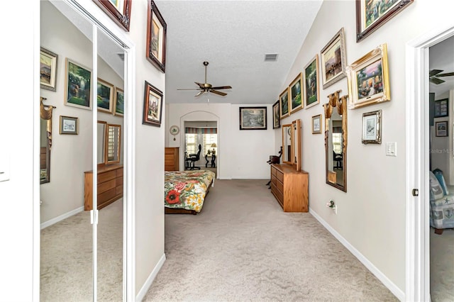 hallway with light colored carpet and a textured ceiling