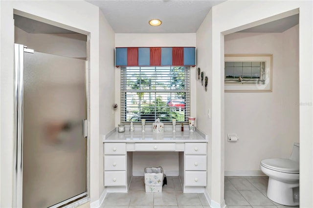 bathroom with tile patterned flooring, vanity, a shower with door, and toilet