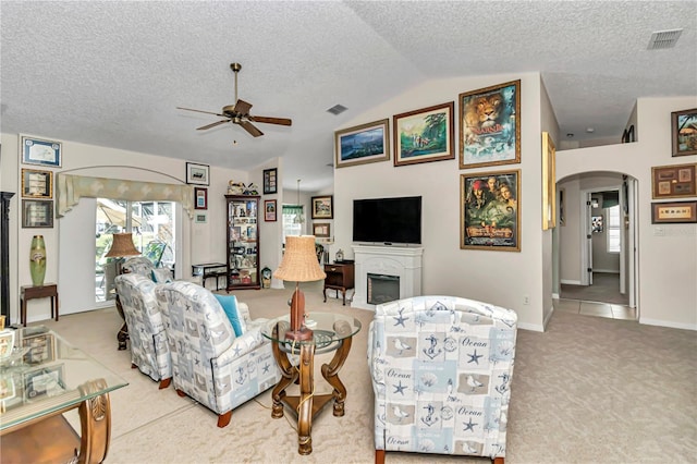 living room featuring lofted ceiling, carpet floors, a textured ceiling, and ceiling fan