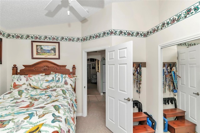 bedroom with lofted ceiling, light colored carpet, a textured ceiling, a closet, and ceiling fan