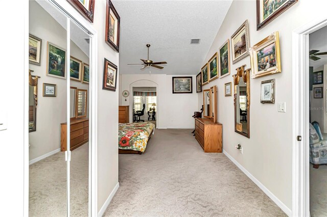 3923 Manor Oaks Ct, Leesburg, FL 34748 - hallway featuring carpet floors, vaulted ceiling, a textured ceiling, and arched walkways