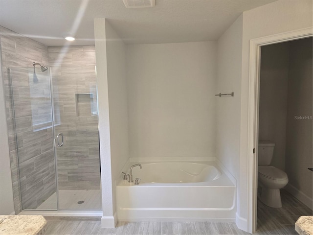 bathroom featuring a textured ceiling, plus walk in shower, and toilet