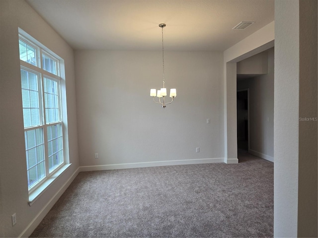 spare room with carpet floors, a chandelier, and plenty of natural light