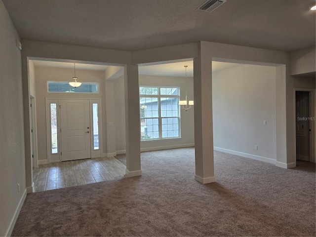 foyer entrance with a textured ceiling, a chandelier, and carpet