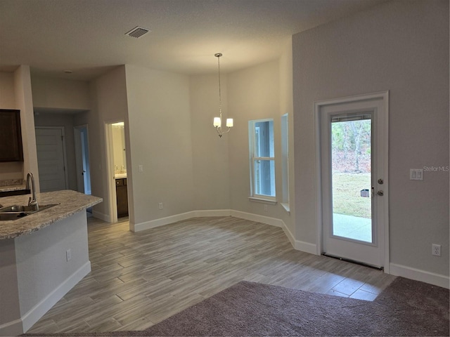 kitchen featuring an inviting chandelier, sink, hanging light fixtures, and light hardwood / wood-style flooring