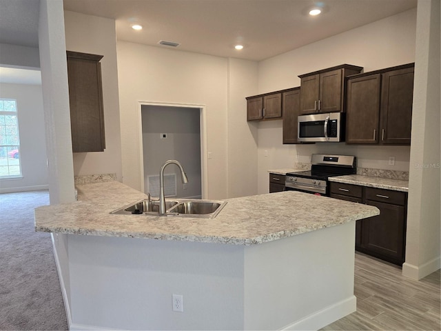 kitchen featuring sink, light hardwood / wood-style flooring, dark brown cabinets, stainless steel appliances, and kitchen peninsula