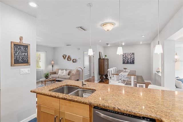 kitchen with sink, light stone countertops, hanging light fixtures, and dishwasher