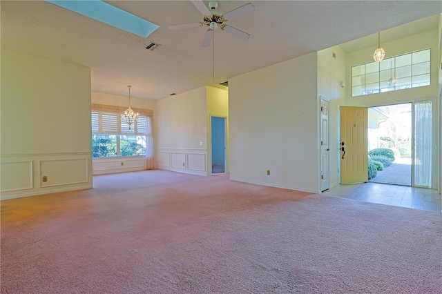 unfurnished room with ceiling fan with notable chandelier, a skylight, and light colored carpet