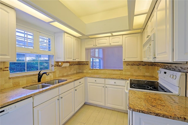 kitchen with sink, white appliances, light stone counters, white cabinets, and decorative backsplash