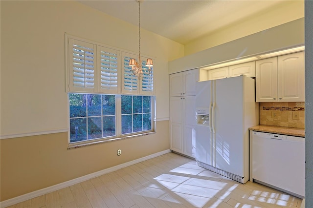 kitchen featuring pendant lighting, white appliances, white cabinetry, decorative backsplash, and a chandelier