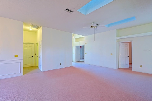 empty room featuring ceiling fan, a skylight, and light colored carpet