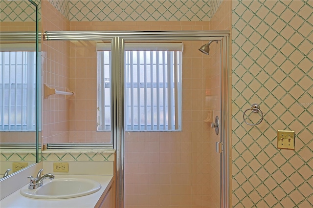 bathroom featuring a healthy amount of sunlight, sink, and an enclosed shower