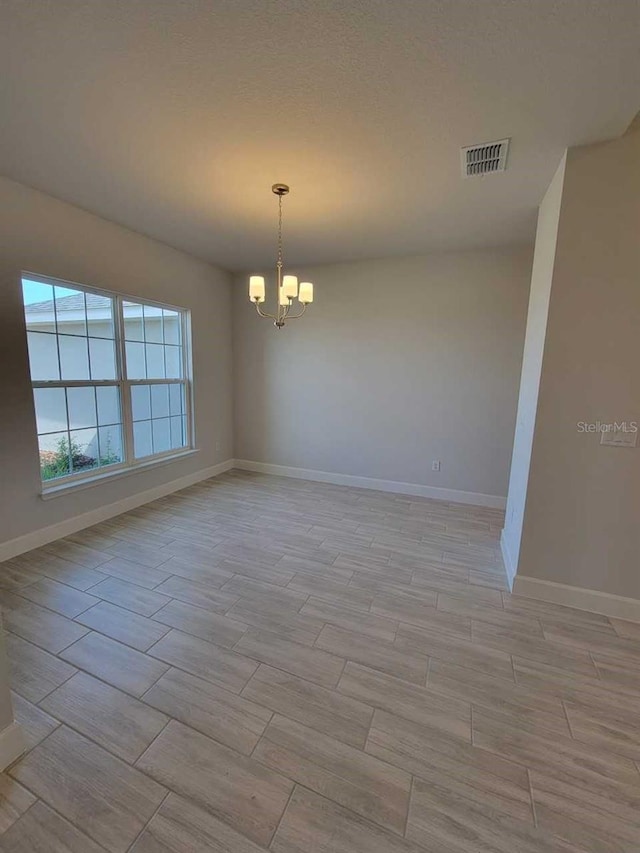 unfurnished room with an inviting chandelier