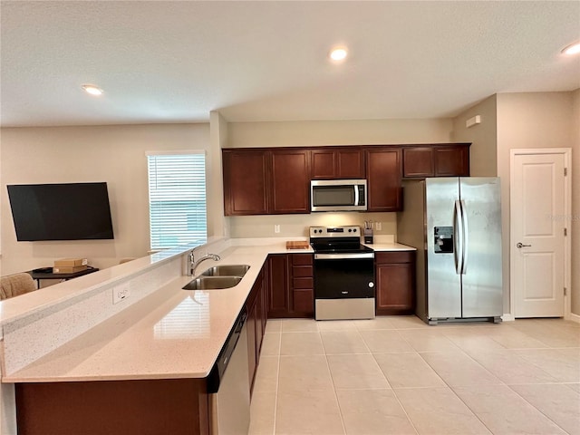 kitchen featuring appliances with stainless steel finishes, sink, light tile patterned floors, dark brown cabinetry, and kitchen peninsula