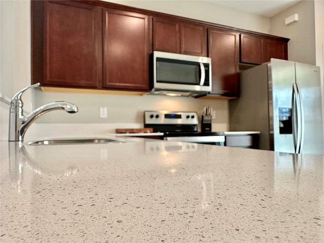 kitchen with sink, light stone countertops, and appliances with stainless steel finishes