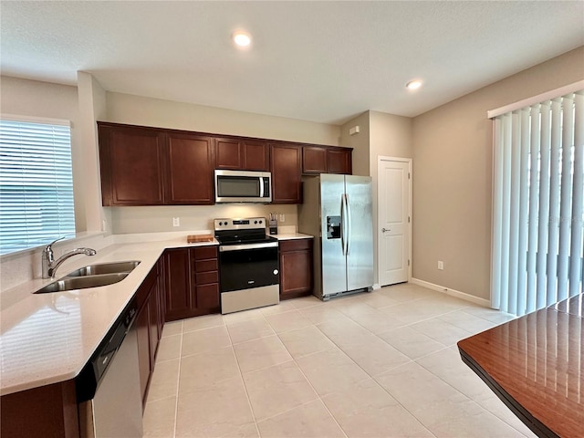 kitchen featuring light tile patterned flooring, stainless steel appliances, sink, and dark brown cabinets