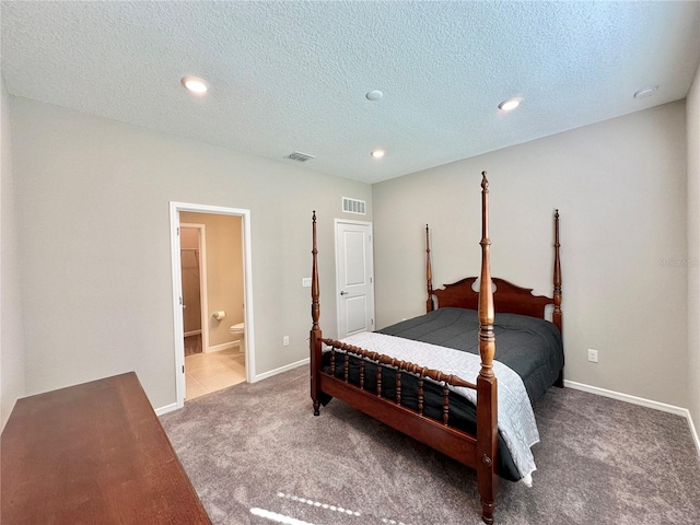 carpeted bedroom with a textured ceiling and ensuite bath