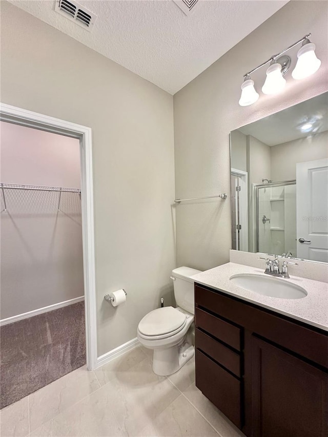 bathroom featuring an enclosed shower, vanity, toilet, and a textured ceiling