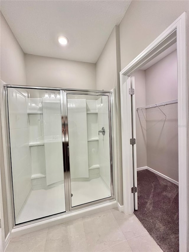 bathroom with tile patterned flooring, a shower with door, and a textured ceiling