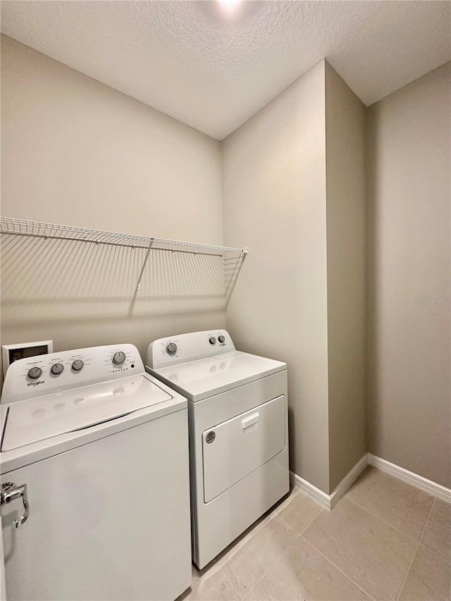 washroom with light tile patterned floors, independent washer and dryer, and a textured ceiling