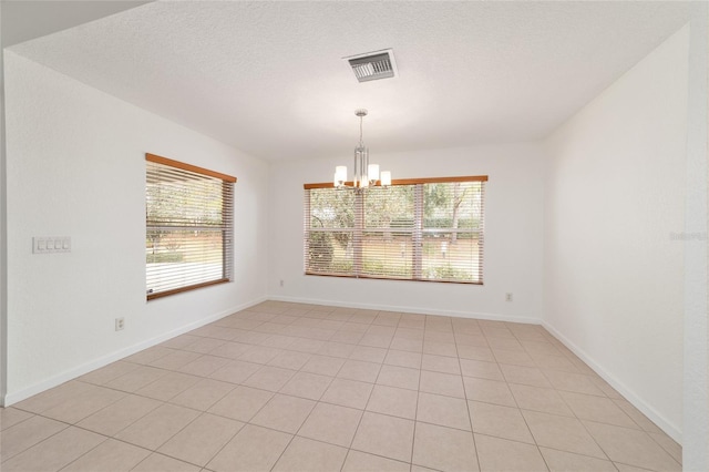 spare room featuring light tile patterned floors, a textured ceiling, and a chandelier