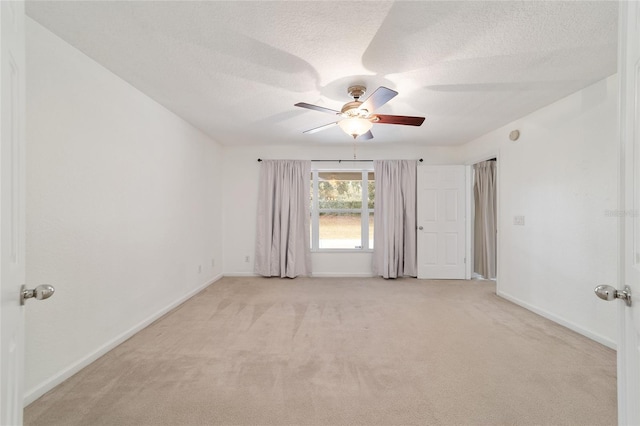 unfurnished room with ceiling fan, light carpet, and a textured ceiling