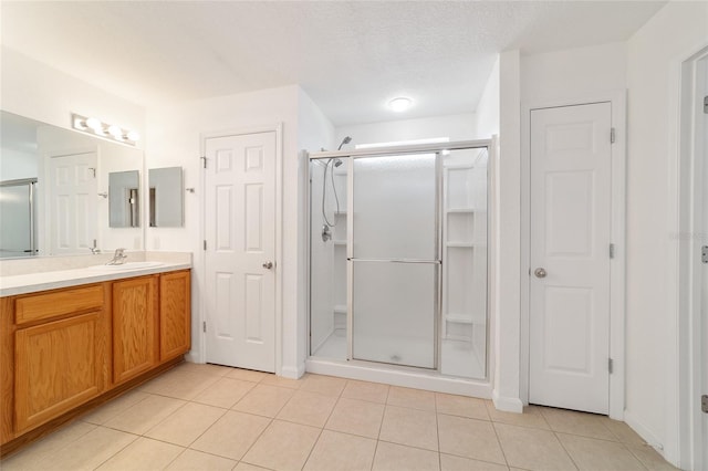 bathroom featuring a shower with door, vanity, and tile patterned floors