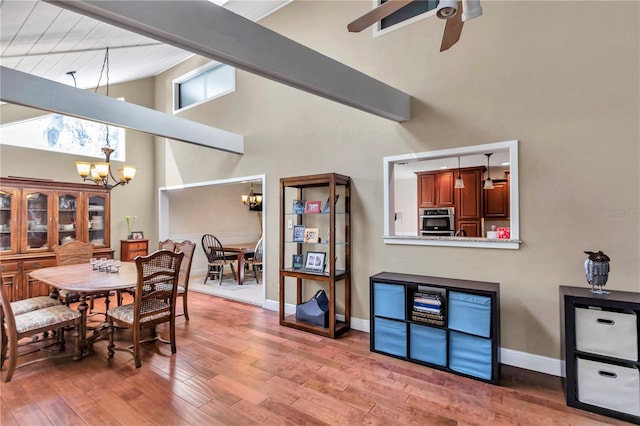 dining room with ceiling fan with notable chandelier, high vaulted ceiling, and hardwood / wood-style floors