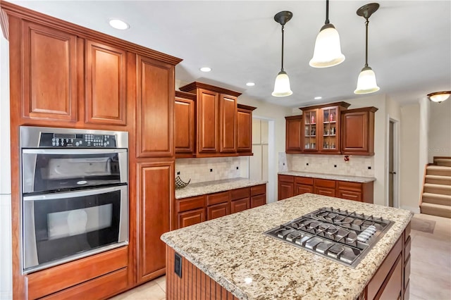 kitchen featuring light stone counters, stainless steel appliances, decorative light fixtures, and decorative backsplash