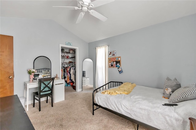 carpeted bedroom featuring vaulted ceiling, a walk in closet, ceiling fan, and a closet