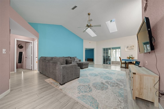 living room with ceiling fan, vaulted ceiling with skylight, and light hardwood / wood-style floors