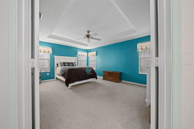 carpeted bedroom featuring a tray ceiling, a textured ceiling, and ceiling fan